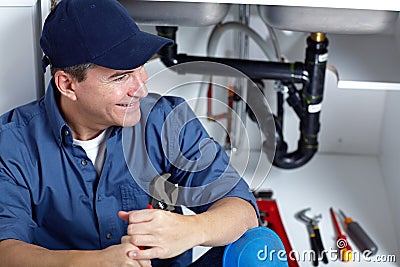 Smiling plumber repairs a sink. Stock Photo