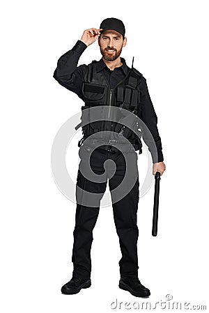 Smiling police officer with baton, adjusting police cap indoors. Stock Photo