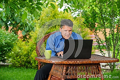 businessman reading good finance news using laptop sitting in his backyard Stock Photo