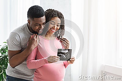 Smiling pregnant black couple showing ultrasound image of their baby Stock Photo