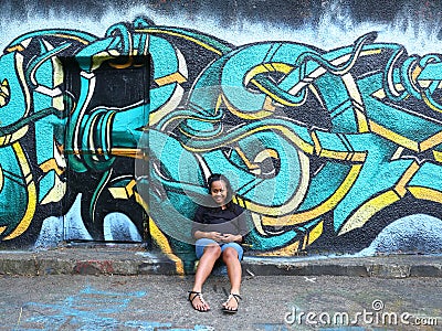 Smiling pregnant girl sitting by door with abstract street art Editorial Stock Photo