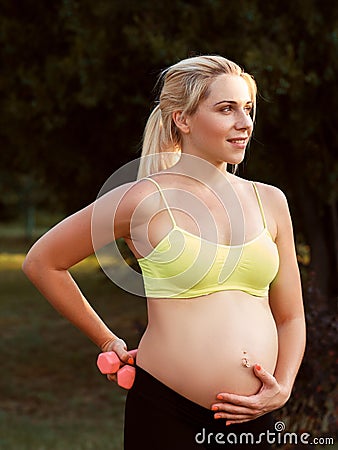 Smiling pregnant woman caress her belly at nature Stock Photo