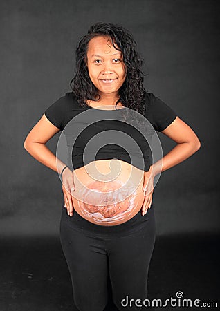 Smiling pregnant woman holding belly with drawing of baby Stock Photo