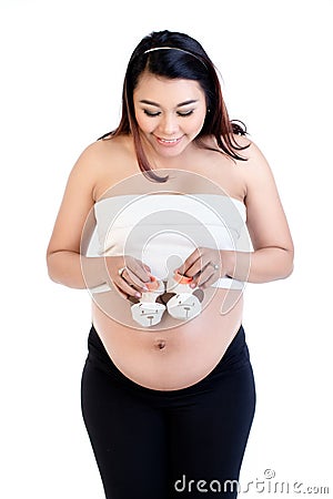 Pregnant woman holding pair of baby shoes over her belly Stock Photo