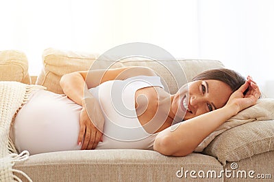 Smiling pregnant woman under blanket Stock Photo