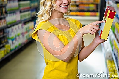 Smiling pretty blonde woman pointing a box Stock Photo