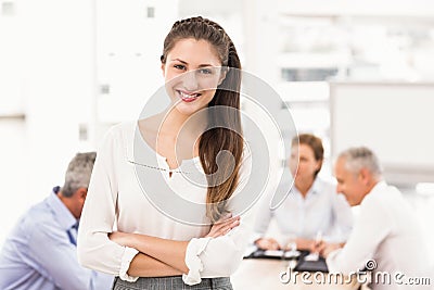 Smiling pretty businesswoman in front of colleagues Stock Photo