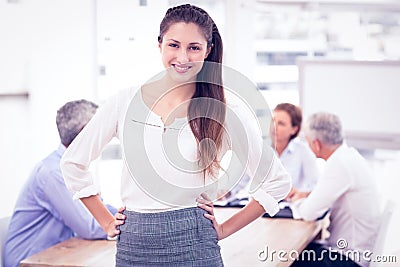 Smiling pretty businesswoman in front of colleagues Stock Photo