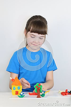 Smiling pretty girl molds toys from plasticine on table Stock Photo