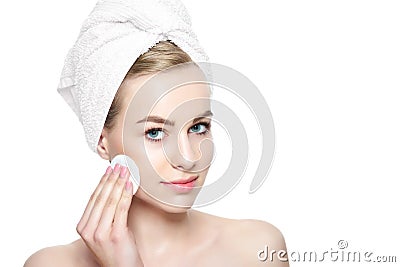 Smiling pretty girl with perfect complexion cleansing her face using soft cosmetic cotton pad. Isolated on white background Stock Photo