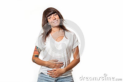 A smiling pretty woman in casual clothes holds her stomach with hands. White background. Concept of good digestion and helthy Stock Photo