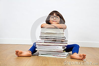 Smiling primary child with eyeglasses leaning on pile of books Stock Photo