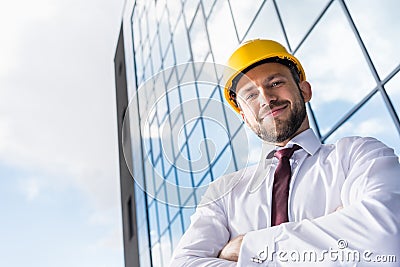 Smiling professional architect in hard hat against building Stock Photo