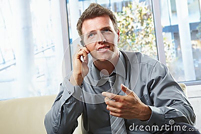 Smiling professional on phone with gesture Stock Photo