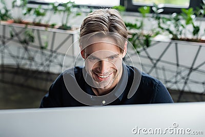 Smiling programmer looking at blurred computer Stock Photo