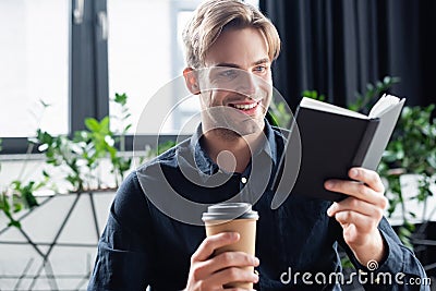 Smiling programmer looking at notebook and Stock Photo