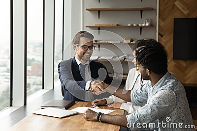 Male realtor handshake biracial couple clients at meeting Stock Photo