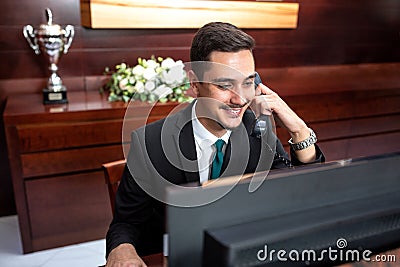 Smiling receptionist tending to hotel needs Stock Photo