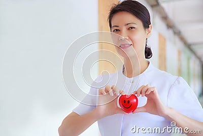 Smiling Red heart held by smiling female nurse`s hand in health care hospital or clinic. Professional, Specialist, Experienced Stock Photo