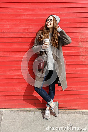 Smiling relaxed young woman standing and drinking take away coffee Stock Photo