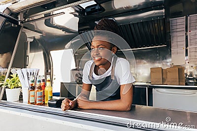Smiling saleswoman in apron leaning counter standing in a food truck Stock Photo