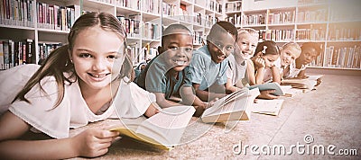 Smiling school kids lying on floor reading book in library Stock Photo