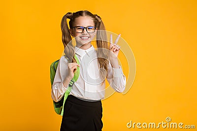 Smiling Schoolgirl Gesturing Victory Sign In Studio Stock Photo