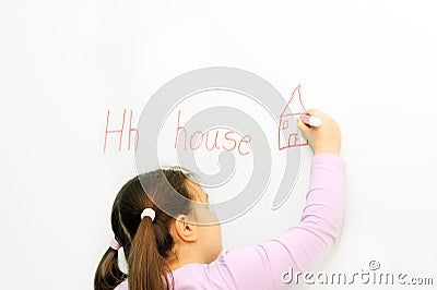 Smiling schoolgirl learning to write letter H Stock Photo