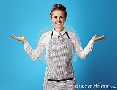 Smiling scrubwoman presenting something on empty palm on blue Stock Photo