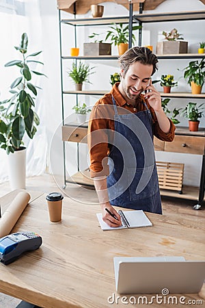 Smiling seller talking on smartphone and Stock Photo