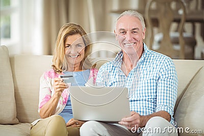 Smiling senior couple doing online shopping on laptop in living room Stock Photo