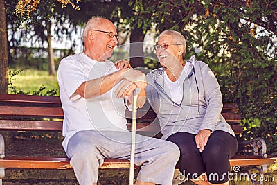 Smiling senior couple sitting on a park bench Stock Photo