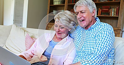 Senior couple using laptop in living room. Smiling senior couple using laptop in living room at home stock footage Senior couple using laptop in living room. Smiling senior couple using laptop in living room at home stock footage