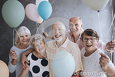 Smiling senior friends with colorful balloons enjoying meeting Stock Photo