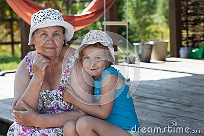 Smiling senior grandmother and happy grandchild embracing on summer veranda, copyspace Stock Photo