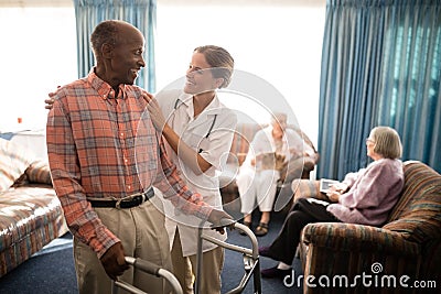 Smiling senior man with walker looking at female doctor against window Stock Photo