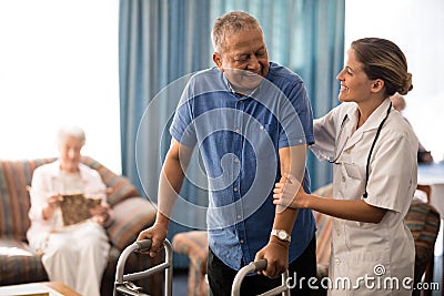 Smiling senior man with walker looking at female doctor Stock Photo