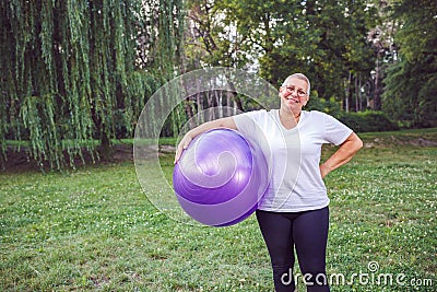 Smiling senior woman with fitness balls in park Stock Photo