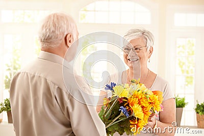 Smiling senior woman receiving bouquet Stock Photo