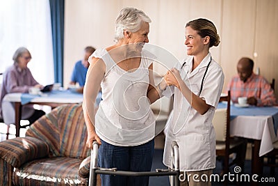 Smiling senior woman with walker looking at female doctor Stock Photo