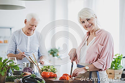 Smiling senior woman cutting tomatoes Stock Photo