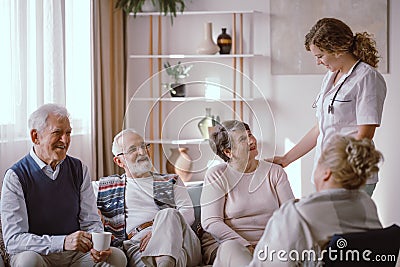 Seniors talking with nurse in the retirement home Stock Photo