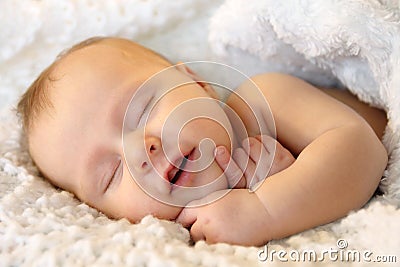 Smiling Sleeping Newborn Baby Girl Wrapped in White Blanket Stock Photo