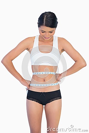 Smiling slim woman measuring her waist Stock Photo