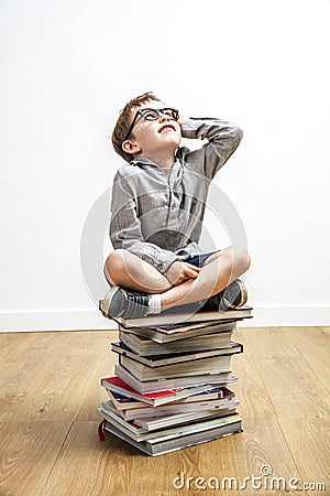 Smiling smart child seated on top of books for culture Stock Photo