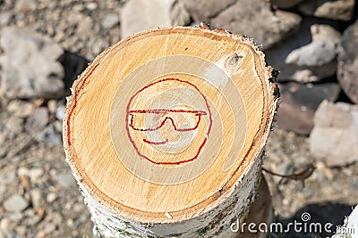smiling smiley with glasses painted in red. Illustration of smiley emoticon painted on log. Positive thinking concepts Stock Photo