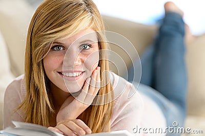 Smiling student girl read book lying sofa Stock Photo