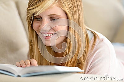Smiling student teenager reading book on sofa Stock Photo