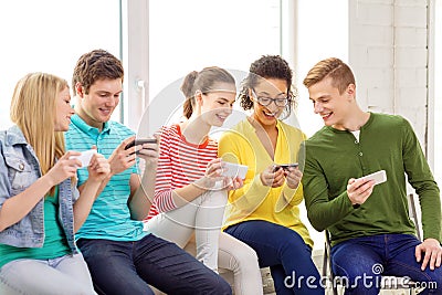 Smiling students with smartphone texting at school Stock Photo