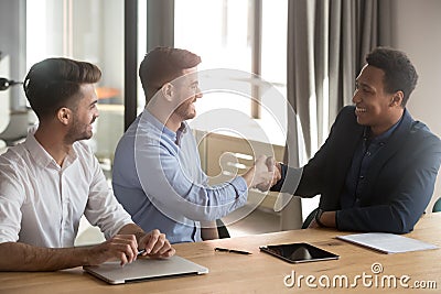 Smiling team leader handshaking with black client Stock Photo